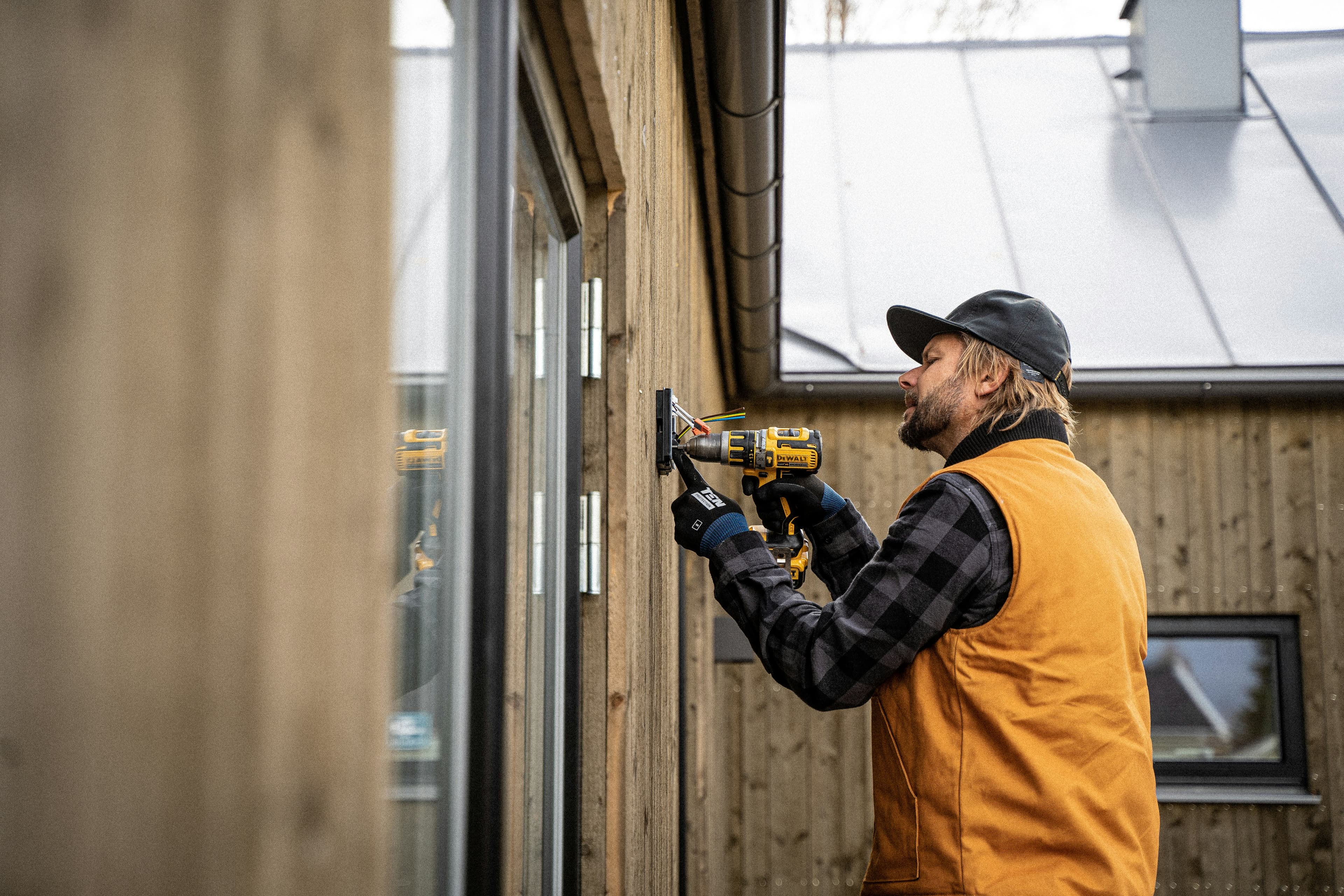Handyman drilling exterior window trim on a home