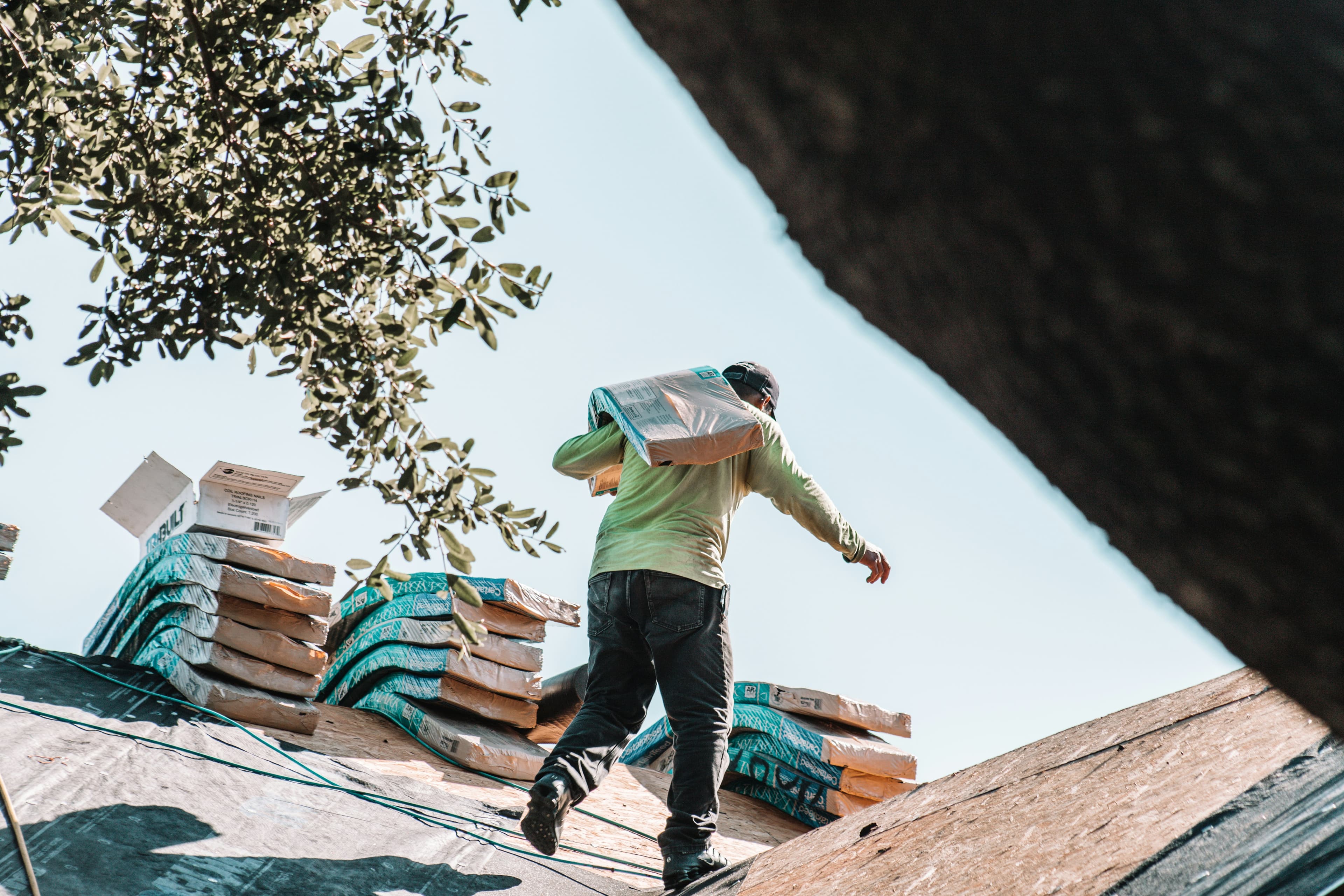 Roofer carrying a bundle of shingles across a roof